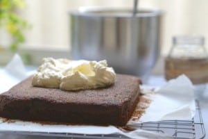 Adding the cream topping to The Best Gluten Free Chocolate Cake